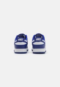 Modré kožené tenisky Nike s bílými akcenty, nízký design, rýhovaná textura a gumová podrážka, s polstrovaným límcem a jazykem.