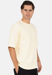 Lichtgeel T-shirt met korte mouwen, een ronde hals en een losse pasvorm. De stof is zacht katoen met een gladde textuur zonder versieringen.