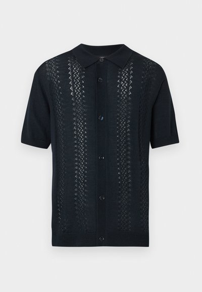 Μαύρο πουκάμισο με κοντά μανίκια και κουμπιά, με μυτερό γιακά και κάθετες ριγέ υφές δαντέλας στο μπροστινό μέρος.