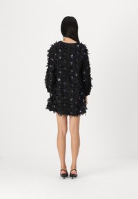 Vestido preto com um design floral texturizado, apresentando detalhes em roxo. Mangas longas e uma bainha curta, feito de material suave.