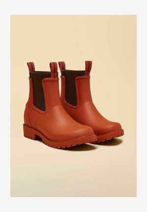 Red waterproof ankle boots with a smooth rubber exterior, elastic side panels in dark brown, and textured soles for grip.