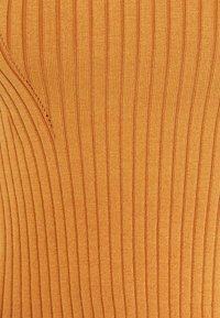 Gros plan d'un tissu tricoté côtelé orange montrant des lignes verticales texturées et des détails de points de tricot.