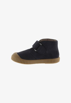 Navy suede ankle boot with velcro strap, rubber sole, and rounded toe. Features textured upper and contrast-colored outsole.