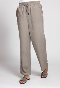 Leichte, graue Hosen mit elastischem Bund und Kordelzug. Glatte Textur und gerade geschnittene Beine, kombiniert mit schwarz-weißen Pantoletten mit Muster.