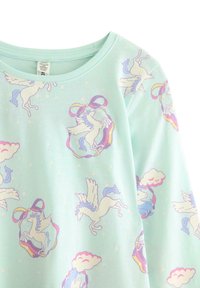 Hellgrünes Langarmoberteil mit einem wiederholten Muster aus Einhörnern, Wolken und Bändern in Pastellfarben. Weiches, bequemes Material.