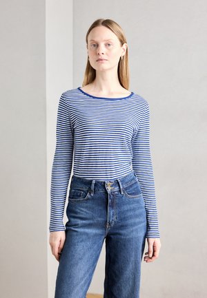 Haut ajusté à manches longues avec des rayures horizontales bleu marine et blanches, accompagné de jeans en denim bleu taille haute. Encolure ronde simple, texture douce.