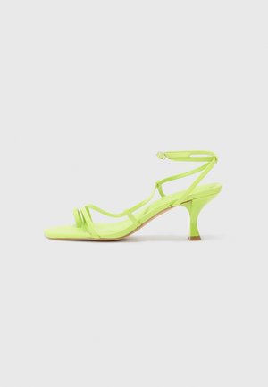 Neon groene hoge hak sandaal met een vierkante neus, dunne bandjes, enkelgesp en een gebogen hak. Gladde stof met een glanzende afwerking.