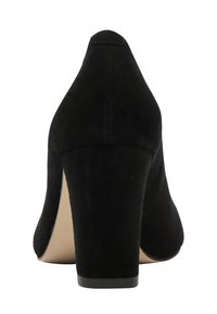 Schwarze Wildleder-Pump mit hohen Absätzen, abgerundeter Spitze und breitem Absatz, von hinten vor einem weißen Hintergrund gezeigt.
