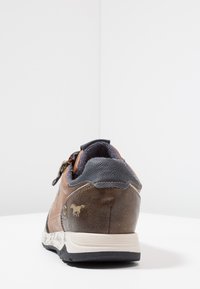 Baskets en cuir marron avec un design texturé, des accents bleus contrastés et un détail logo doré sur le talon. Semelle extérieure en caoutchouc.