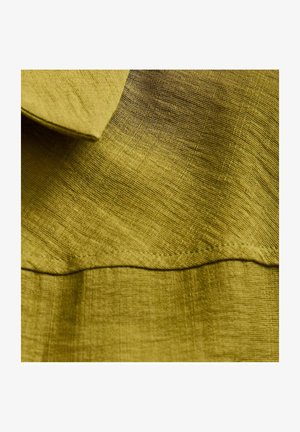 Olijfgroen stof met een gestructureerde afwerking. Heeft een opgevouwen kraag en een zichtbare naad langs de onderzoom.