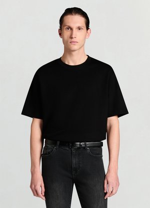 T-shirt nera a maniche corte con vestibilità rilassata e scollo tondo, abbinata a jeans denim scuri e cintura nera. Tessuto liscio.