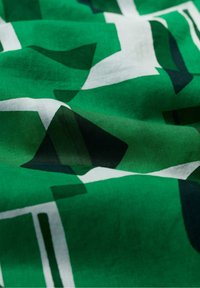 Groene stof met abstracte witte en donkergroene geometrische patronen. Zachte textuur, glad materiaal, dat een gelaagd uiterlijk laat zien.
