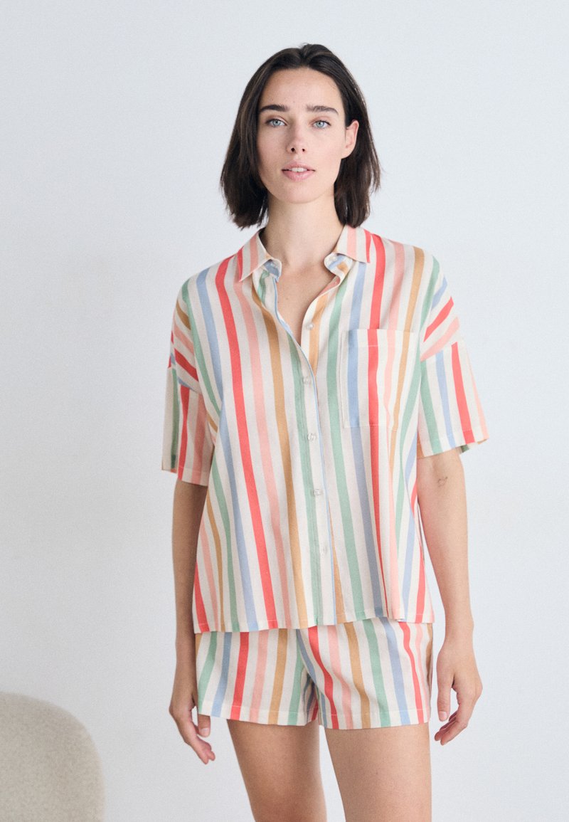 Conjunto de camisa de manga corta con cuello y pantalones cortos en rayas multicolores. Hecho de tela ligera con un corte relajado y un único bolsillo en el pecho.