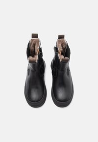 Bottines en cuir noir avec une doublure en fourrure douce couleur beige, fermeture éclair sur le côté et semelle en caoutchouc robuste.