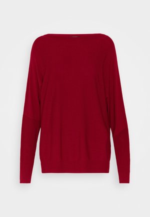 Langærmet, løs rød sweater med bred halsudskæring og ribstrikkede manchetter og kant, vist på ensfarvet baggrund.