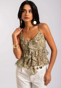Top sin mangas de estampado de leopardo en tela transparente con capas con volantes, con escote en V y tirantes delgados, combinado con pantalones de color claro.