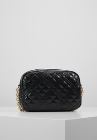 Vadderad svart läderväska med rektangulär form, guldkedjestraps och slät yta. Har diamantmönster och dragkedjestängning.