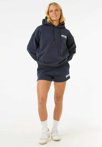 Marineblauwe hoodie van katoenmix met trekkoorden en logo, gecombineerd met bijpassende shorts. Witte sneakers en sokken maken de outfit compleet.