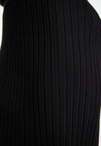 Schwarzer gerippter Stoff, der vertikale Linien und eine glatte Textur zeigt. Das Design weist eine enganliegende Silhouette auf, die die Dehnbarkeit des Materials betont.