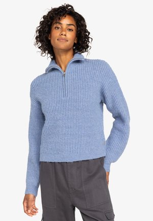 Pull en tricot bleu clair avec un col zippé mi-hauteur, texture côtelée et manches longues. Fini avec un petit logo au niveau de l'ourlet.