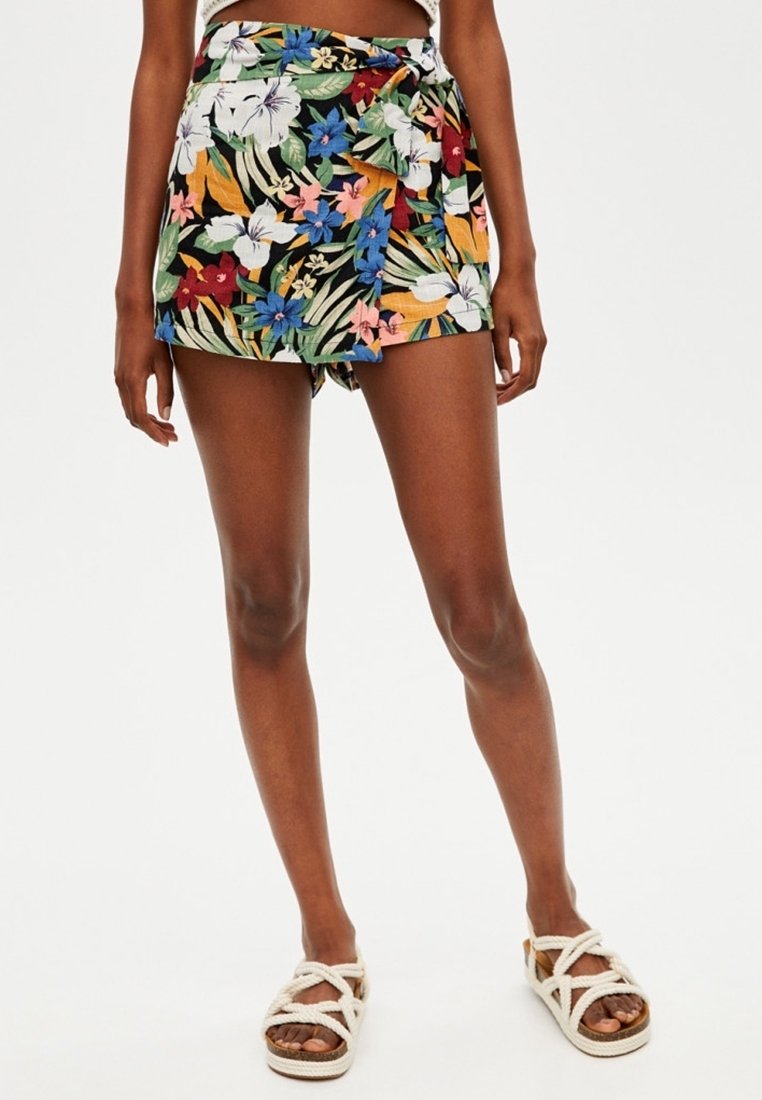 Pantalones cortos con estampado floral que presentan un fondo negro, cinturilla anudada y flores multicolores vibrantes. Fabricados con material ligero.