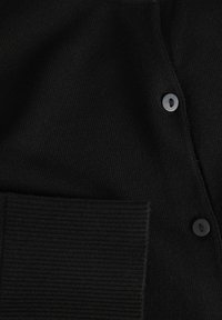 Svart stickad cardigan med ribbad textur, knäppning fram och en framficka i ett fast tyg.