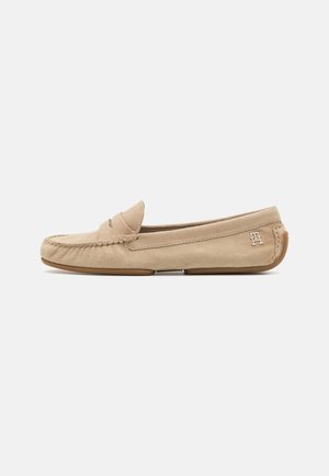 Mocassins en daim beige avec un bout cousu, une bride décorative et une semelle en caoutchouc. Détail du logo à l'arrière. Design profil bas.