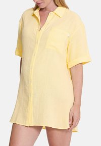 Korte mouwen, knoopsluiting shirt in lichtgeel, gemaakt van textuurstof met een borstzak en opgerolde mouwen. Zacht en ademend ontwerp.