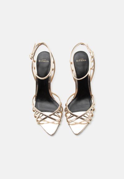 Ζευγάρι χρυσά σαγιονάρια με ψηλό τακούνι, μυτερά δάχτυλα και λουριά με πόρπη στον αστράγαλο, μαύρες εσωτερικές σόλες με την επιγραφή "Alexandre Birman".