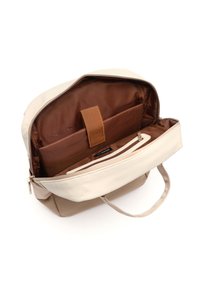 Beige and tan fabric backpack with a zipper closure, featuring a brown interior, a padded compartment, and a small zip pocket.