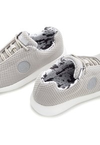 Light grey sneakers with a textured mesh upper, white soles, and a black and white patterned interior. Logo detail on the outer side.