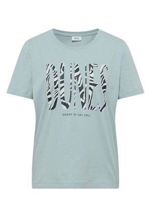 T-shirt à manches courtes bleu clair avec le texte « DUNES » à motif zèbre et un texte plus petit « NOMAD OF THE SOUL » imprimé en dessous, au niveau de la poitrine.