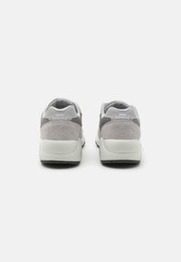 Szürke velúr és hálós futócipők fehér márkázással, lekerekített sarkakkal és texturált talppal, párnázott nyakkal és kontrasztos díszítéssel.