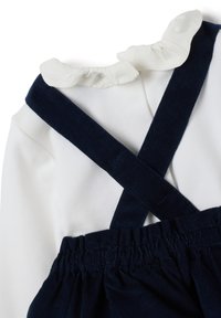 Top bianco a maniche lunghe con scollo arricciato e spalline incrociate in velluto a coste blu navy, vita arricciata e texture morbida.