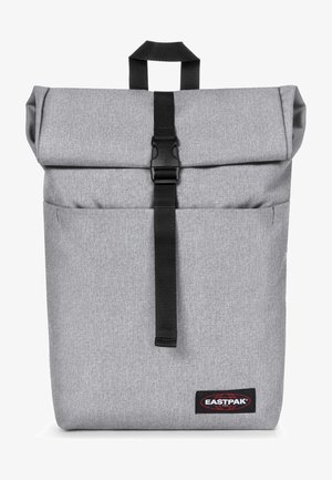 Grijze roll-top rugzak met zwarte riemsluiting, gestructureerde stof, voorvak en Eastpak-logo rechtsonder.