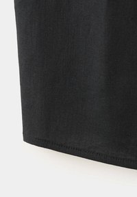 Tissu noir avec une ligne de couture visible près du bord, montrant la texture et le tissage sur un fond blanc uni.