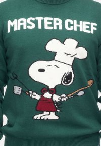 Maglione verde lavorato a maglia con la scritta "MASTER CHEF" in bianco sopra Snoopy, che indossa un cappello da cuoco e un grembiule rosso, mentre tiene un cucchiaio e una spatola.