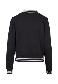 Veste bomber noire à manches longues avec col, poignets et ceinture côtelés à rayures blanches, vue de dos.