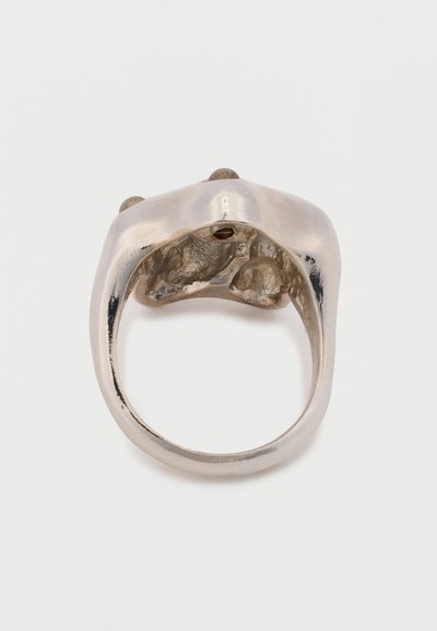 Zilveren ring met een organisch, textuur oppervlak; heeft gladde, afgeronde randen en drie kleine, ronde accenten aan de bovenkant.