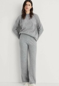 Maglione grigio in maglia e pantaloni a gamba larga coordinati in materiale morbido. Il maglione presenta un colletto tondo e polsini a costine. Vestibilità rilassata.