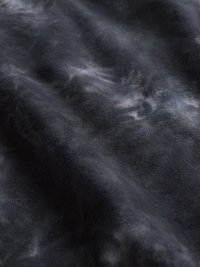 Κοντινό πλάνο μαύρου υφάσματος με γκρι και λευκά σχέδια tie-dye που δημιουργούν μια μαρμάρινη υφή.