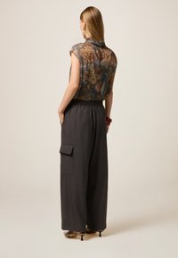 Blusa clara con estampado floral, combinada con pantalones de pierna ancha en gris oscuro que cuentan con una cintura elástica y dos bolsillos laterales.