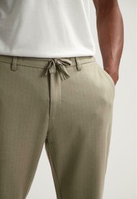 Lichtgroene, textuurstof linnedraad trousers met een trekkoord in de taille en subtiele verticale strepen. Bevat zijzakken en heeft een getailleerde pasvorm.