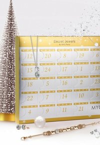 Calendario dell'Avvento di gioielli con un design oro e bianco, caratterizzato da porte numerate, una collana d'argento, orecchini assortiti e un bracciale di perline.