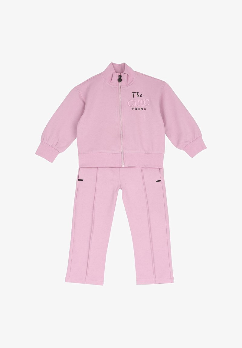 Ensemble deux pièces rose clair avec veste zippée arborant le texte "The CHIC TREND" et pantalon droit assorti avec des détails latéraux.