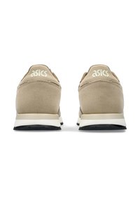 Beiga träningsskor med ovandel i mocka, böjd design och vit mellansula. Har ASICS-logotypen i ljus text på hälen.