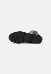 Suela de bota de goma negra con un patrón de herradura profundo para tracción, punta redondeada y bordes reforzados para mayor durabilidad.