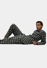 Pijama de cuadros en tonos negro y gris, que cuenta con camisa de botones, mangas largas y pantalones de corte relajado y textura suave.