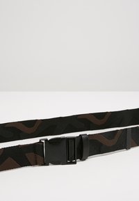 Black and brown patterned fabric belt with a plastic buckle and adjustable strap. Features a camouflage design and textured material.