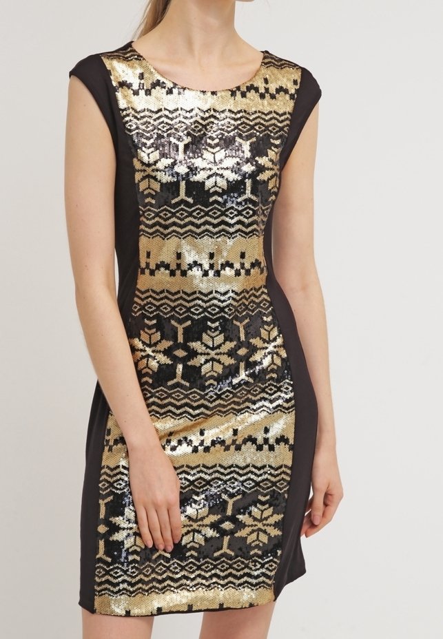 Robe noire sans manches avec motif géométrique et flocons de neige en sequins dorés et noirs sur le devant, portée par une personne debout.